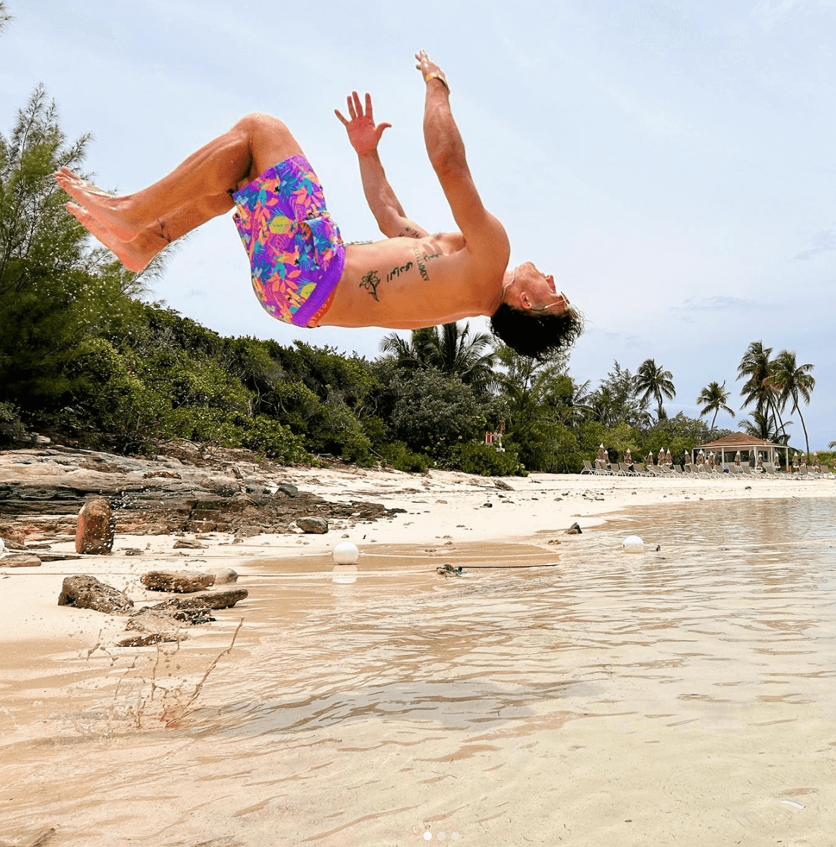 A guy doing a backflip into the ocean