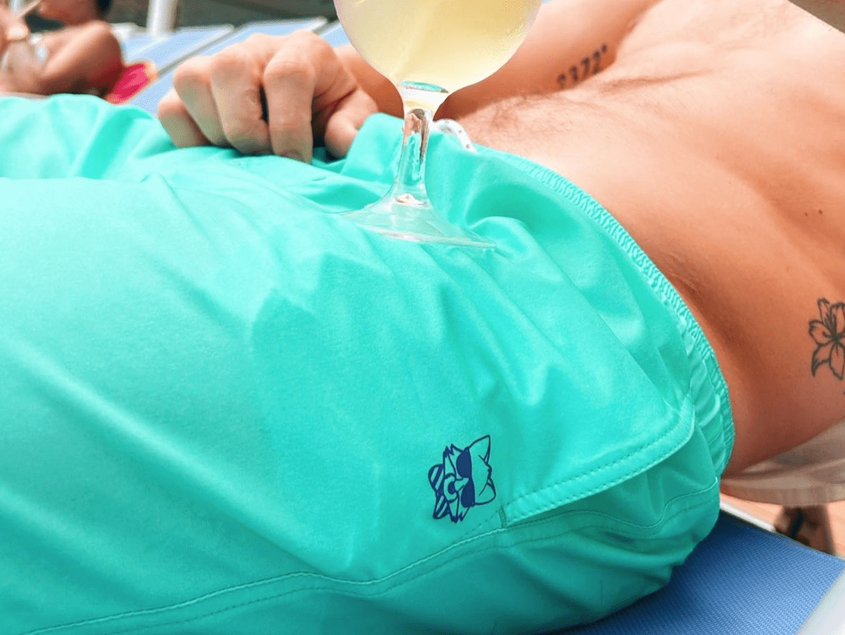 man wearing turquoise nylon party shorts