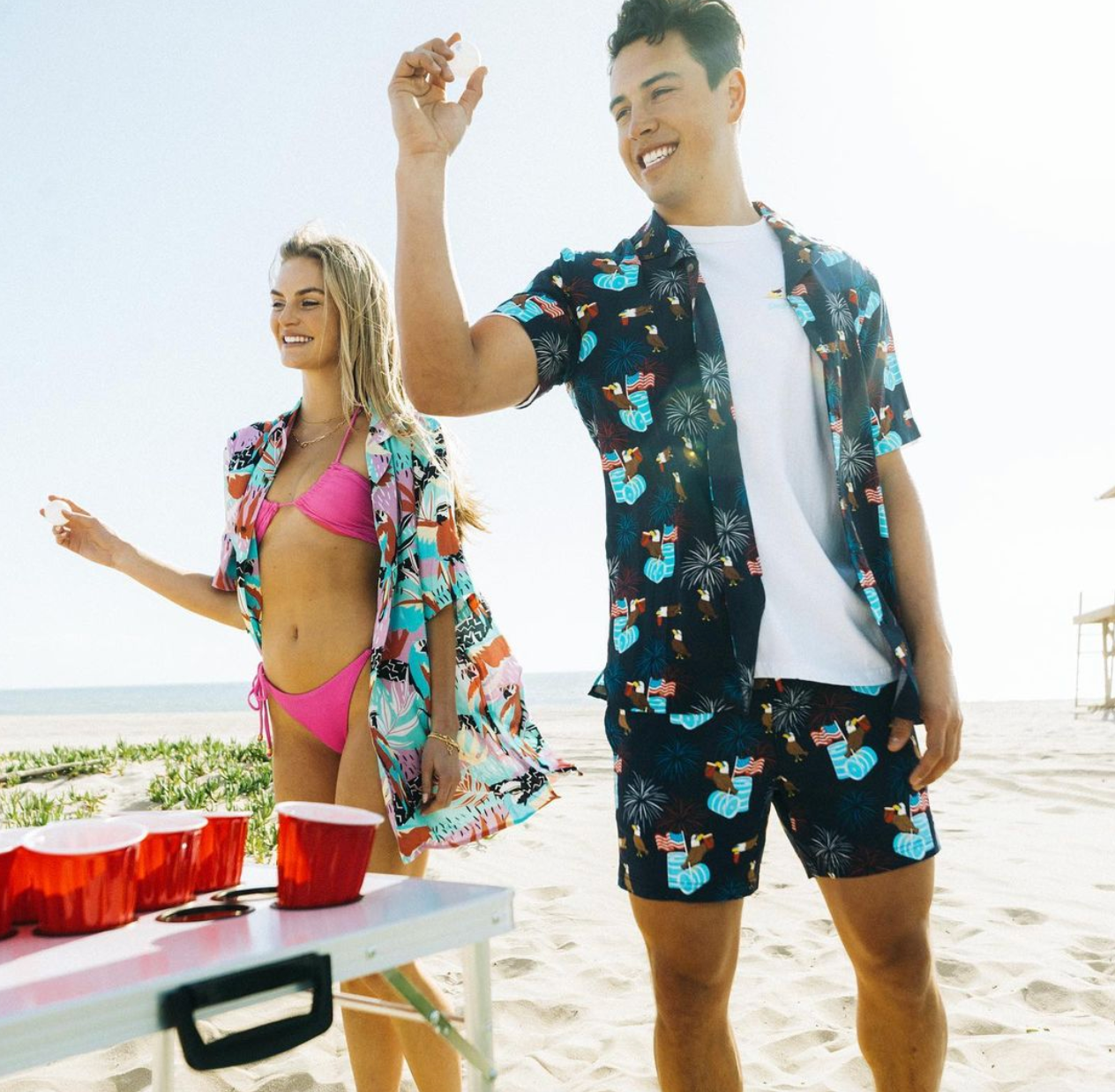 A man and woman playing beer pong at a beach